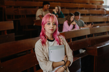 Confident Student Posing in Empty Lecture Hall with Notebook
