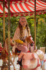teenage girl riding carousel in autumn park. autumn season. autumn day