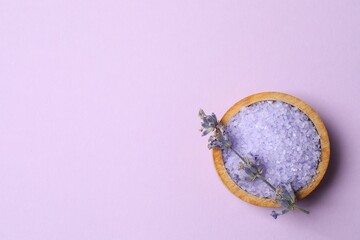 Top view of lavender flowers and bath salts on a purple background
