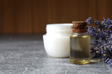 Herbal oil, cream and lavender flowers on gray background - cosmetic procedure. Lavender essential oil still life

