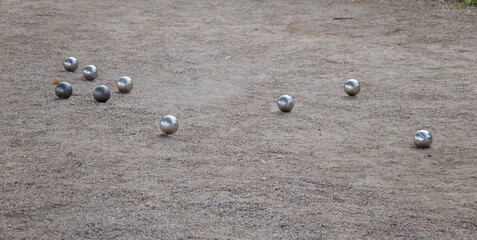 Petanque balls scattered on a gravel playing field during a casual outdoor game