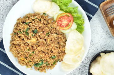 Indonesian fried rice with egg, chicken, vegetables, and crackers