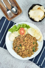 Indonesian fried rice with egg, chicken, vegetables, and crackers