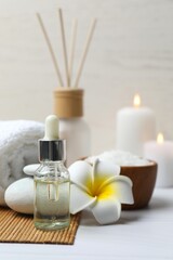 Vertical view of spa composition with oil, white towel, salt and candles on wooden table. Spa and...