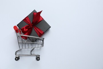 Miniature shopping basket and gift box on white background. Black Friday or holiday shopping