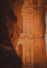 View of Al Khazneh (The Treasury) emerging at the end of the Siq canyon in Petra, Jordan, captured from the shaded narrow passage leading to the monument
