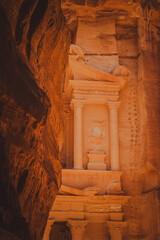View of Al Khazneh (The Treasury) emerging at the end of the Siq canyon in Petra, Jordan, captured from the shaded narrow passage leading to the monument