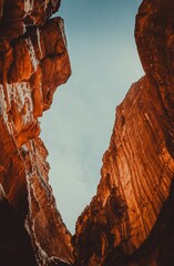 upward view of dramatic sandstone rock formations in Petra, Jordan, showcasing rugged cliff textures and natural mountain shapes carved by time