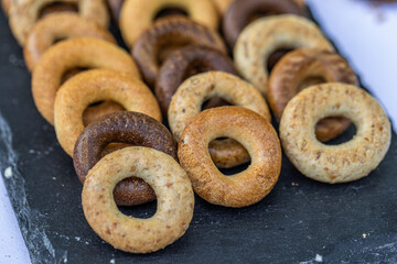 Freshly baked mini bagels on a dark background. Top view. Pretzels in the form of a ring close-up. Small bread circle biscuit. Bowls with different types of bagels.