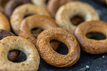 Freshly baked mini bagels on a dark background. Top view. Pretzels in the form of a ring close-up. Small bread circle biscuit. Bowls with different types of bagels.