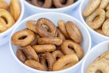 Freshly baked mini bagels on a dark background. Top view. Pretzels in the form of a ring close-up. Small bread circle biscuit. Bowls with different types of bagels.