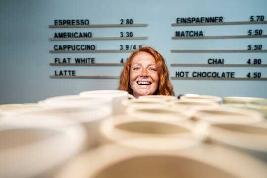 Smiling small business owner in cafe with coffee cups and menu