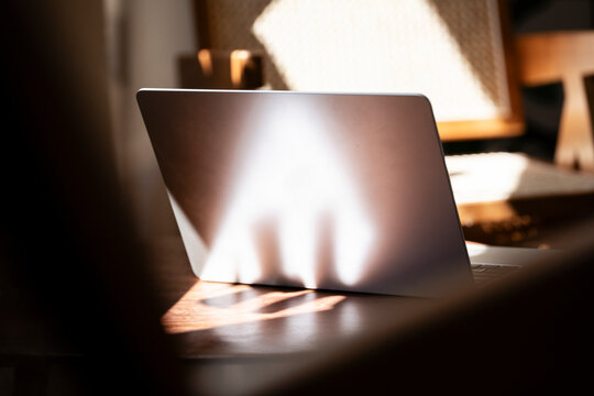 Laptop with sunlight reflection on cafe table in a relaxed setting