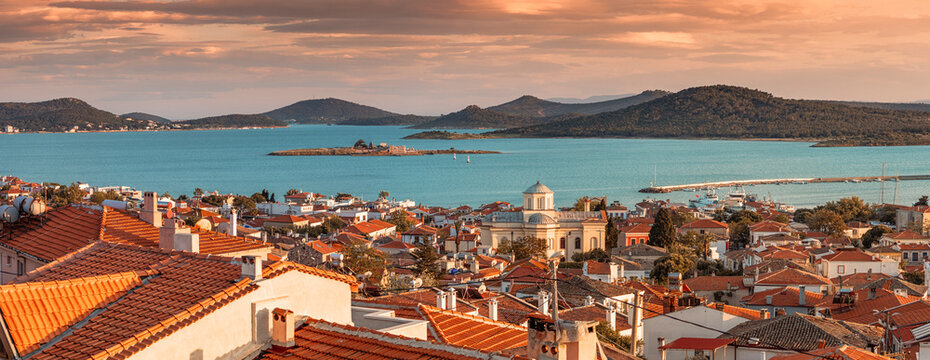 Panoramic sunset view of Cunda Island with red-tiled roofs, Orthodox church, and Aegean Sea in Ayvalik, Turkey