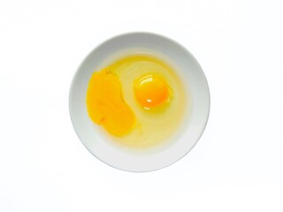 Fresh raw egg yolk in ceramic plate isolated on white background. Raw egg yolk. Cracked egg in a white bowl, ideal for culinary and kitchen themes. Top view.