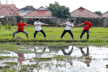 Indonesian Youth Play Tug of War on a Grassy Field, Celebrating National Independence Day