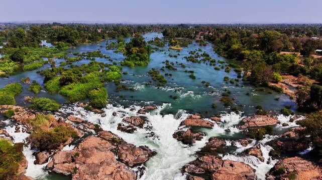 Aerial view of Mekong River rapids near Don Det, Laos, water splitting through rugged rocks and green islets within the Si Phan Don floodplain, where seasonal flows shape the braided river landscape.