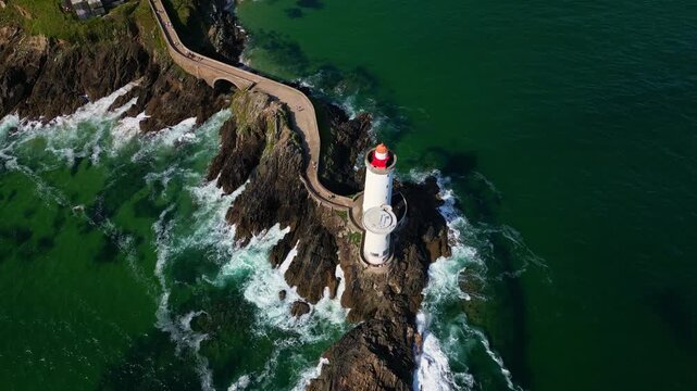Drone shot in total top-down view pushing forward over Petit Minou lighthouse and the winding path leading to it, with waves crashing below. Brittany in France