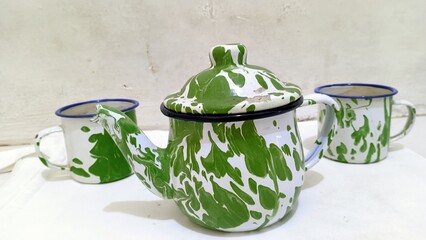 a set of classic Indonesian enamelware, consisting of a green-and-white teapot with a matching pair...