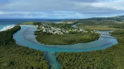 Aerial panoramic pullback showing looping bends of Minnamurra River cutting through vibrant estuarine landscape near homes