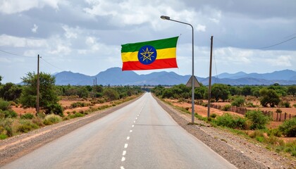 The Ethiopian flag hangs over a long, straight road stretching through a rural, mountainous landscape.