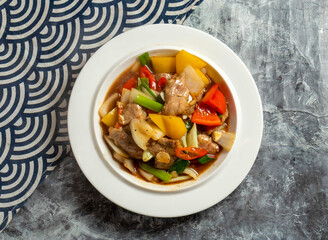 Stir fried pork with bell peppers and onions in a savory sauce in plate top view of Chinese food