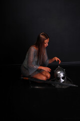 Beautiful woman warrior in chainmail sitting on her knees at sword and helmet low key portrait
