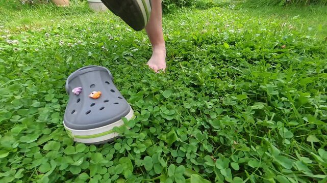 The woman takes off her sandals and stands on the grass with her bare feet. Shot on an action camera. Samara, Russia - 10 July 2025