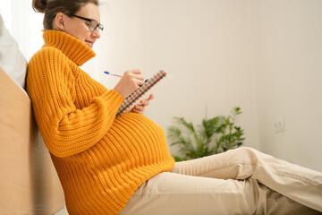 Pregnant woman carefully compiling hospital bag list in comfortable home environment. Heartwarming...