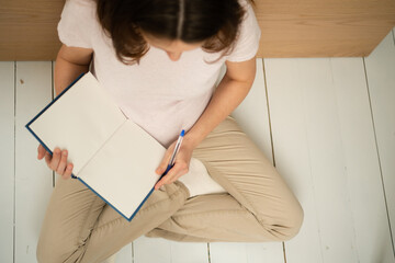 Overhead shot of future mother writing crucial to-do list for maternity period. Detailed...