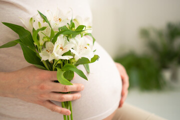 Serene close-up of pregnant woman's hands lovingly touching her baby bump. Heartwarming scene of...