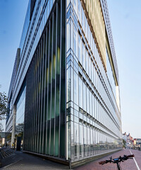 Bicycle in front of the acute-angled glass facade of the office building in the center of the...