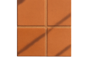 Matte terracotta tiles with fine sand texture and grout under soft light