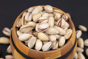 Heap of tasty pistachio nuts in the bowl on dark background