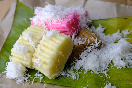 Colorful blocks of gethuk lindri, a traditional Indonesian cassava cake, served on banana leaf and topped with fresh grated coconut.