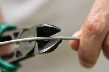 Hands of the master in hold wire cutters and wire closeup . Electronics Repair Idea