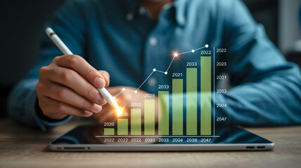 Person using stylus on tablet displaying holographic green bar graph with upward trend hand