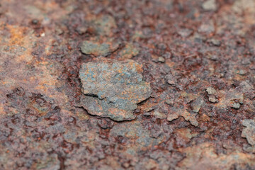 Close-up view of rusty metal showing the rough texture and dark red and gray colors of oxidation and corrosion over an iron surface.