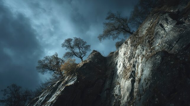Cinematic angle looking up at a massive cliff under moody sky, windblown trees clinging to edges