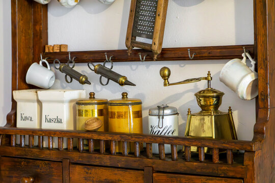 Vintage kitchen shelf with containers, coffee grinders, and enamelware in an old countryside home.