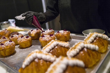 Freshly baked croissant decorated with cranberry jam and sugar icing toppings.