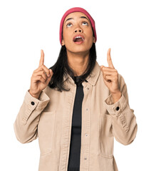 Young Filipino woman in studio pointing upside with opened mouth.