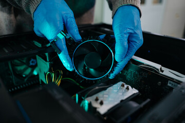 Obraz premium Closeup of technician in gloves holding CPU cooler and heat gun over desktop PC. Ideal image for computer repair, cooling system, and hardware