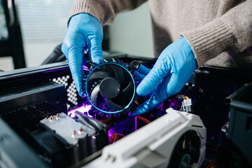 Closeup of technician in gloves holding CPU cooler and heat gun over desktop PC. Ideal image for...