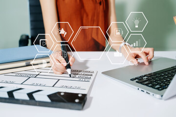 Creative woman working on tablet with digital icons and clapperboard. Modern media, marketing, and...