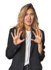 Young businesswoman in a suit rejecting someone showing a gesture of disgust.