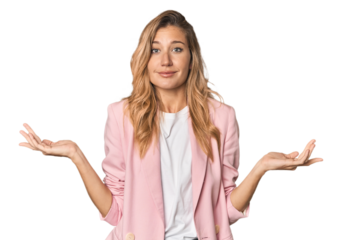 Young blonde in stylish pink suit doubting and shrugging shoulders in questioning gesture.
