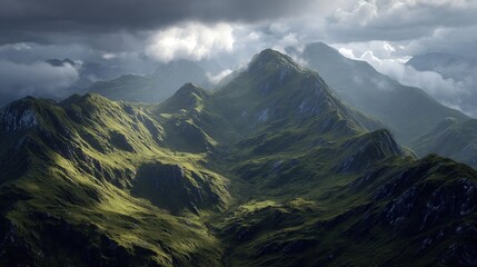 Obraz premium Dramatic, sun-drenched mountain range with lush green slopes, partially shrouded in clouds under a stormy sky, showcasing deep shadows and high peaks