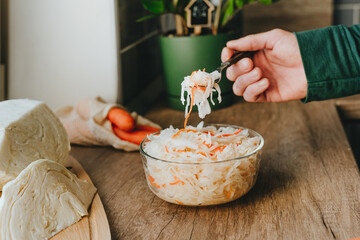 Man holding fork with fresh sauerkraut on the table