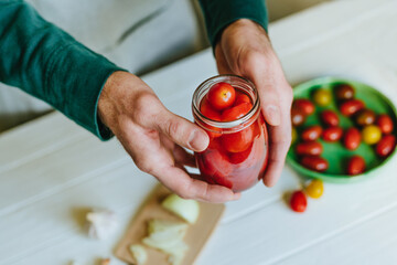 Hands of a person holding pickled cherry tomatoes